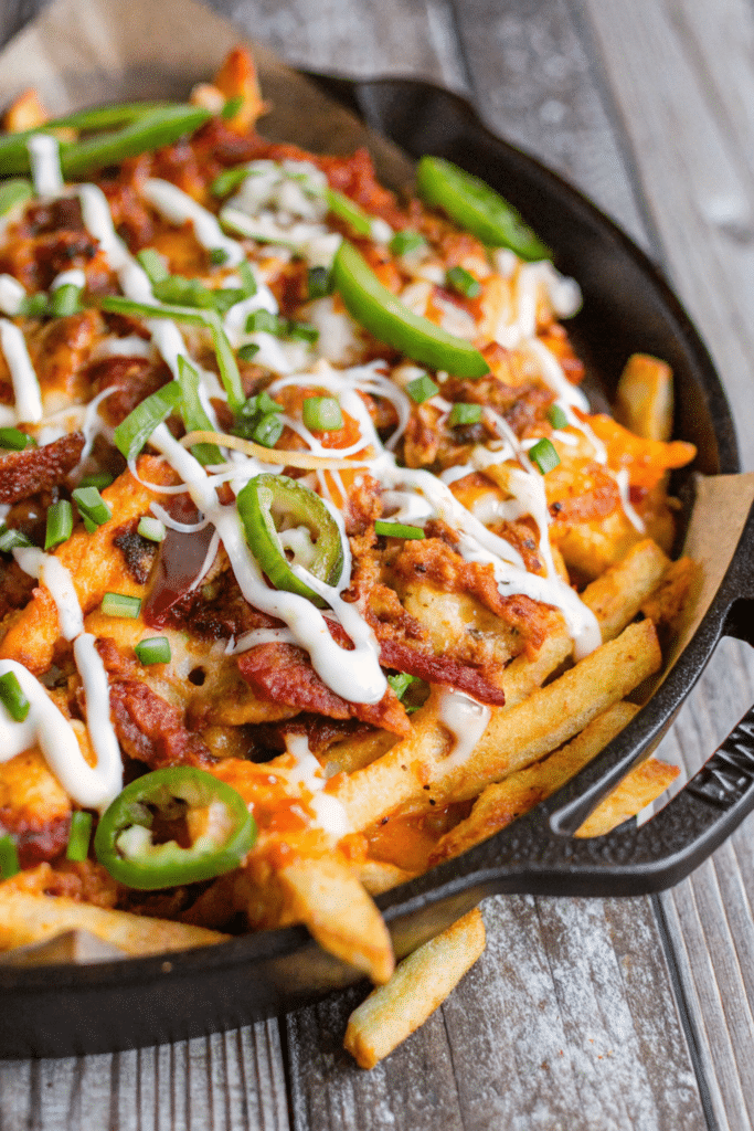 Fully Loaded Fries topped with melted cheese, crispy bacon, and sour cream. Title: Fully Loaded Fries with Bacon and Cheese