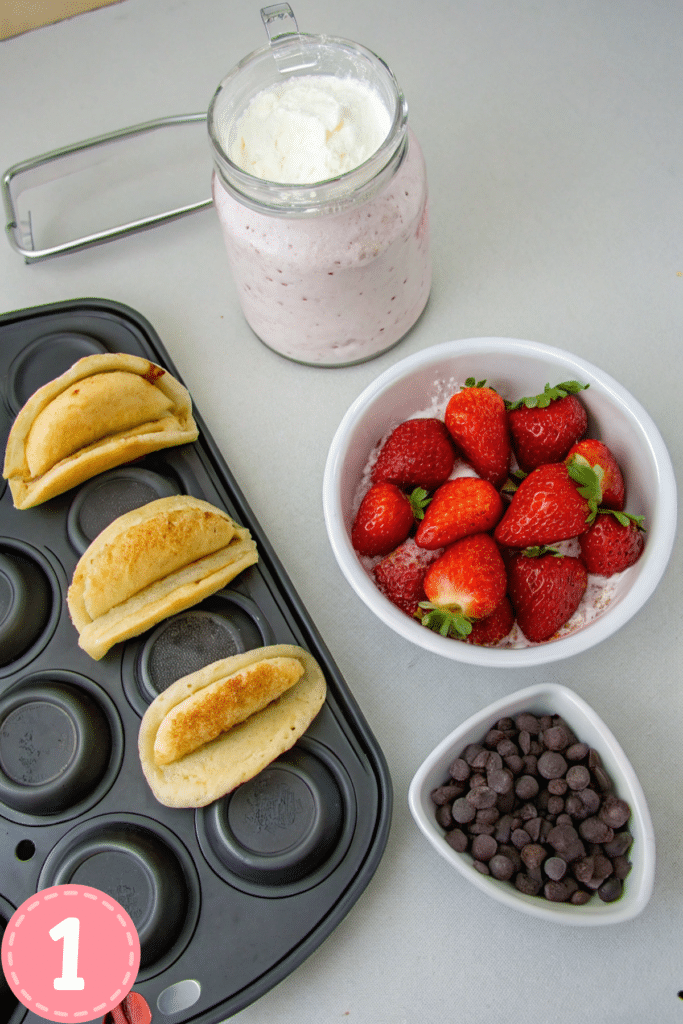 Fluffy pancakes filled with cheesecake mousse, fresh strawberries, and chocolate chips, presented in a red taco holder