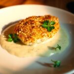 Crispy Parmesan Chicken served on a white plate with a crispy golden crust and garnished with fresh parsley.